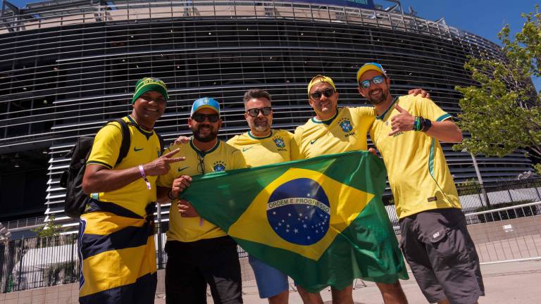 EAST RUTHERFORD, NEW JERSEY - JUNE 13: Brazl fans hold a flag outside of MetLife Stadium on June 13, 2026 in East Rutherford, New Jersey. New York and New Jersey's transportation system will face a major test Saturday as New Jersey's FIFA World Cup schedule begins at MetLife Stadium with Brazil against Morocco. Nearly 80,000 fans will be travelling on NJ Transit trains, shuttle buses, and thousands of Uber and Lyft rides to and from the venue. Adam Gray/Getty Images/AFP (Photo by Adam Gray / GETTY IMAGES NORTH AMERICA / Getty Images via AFP)